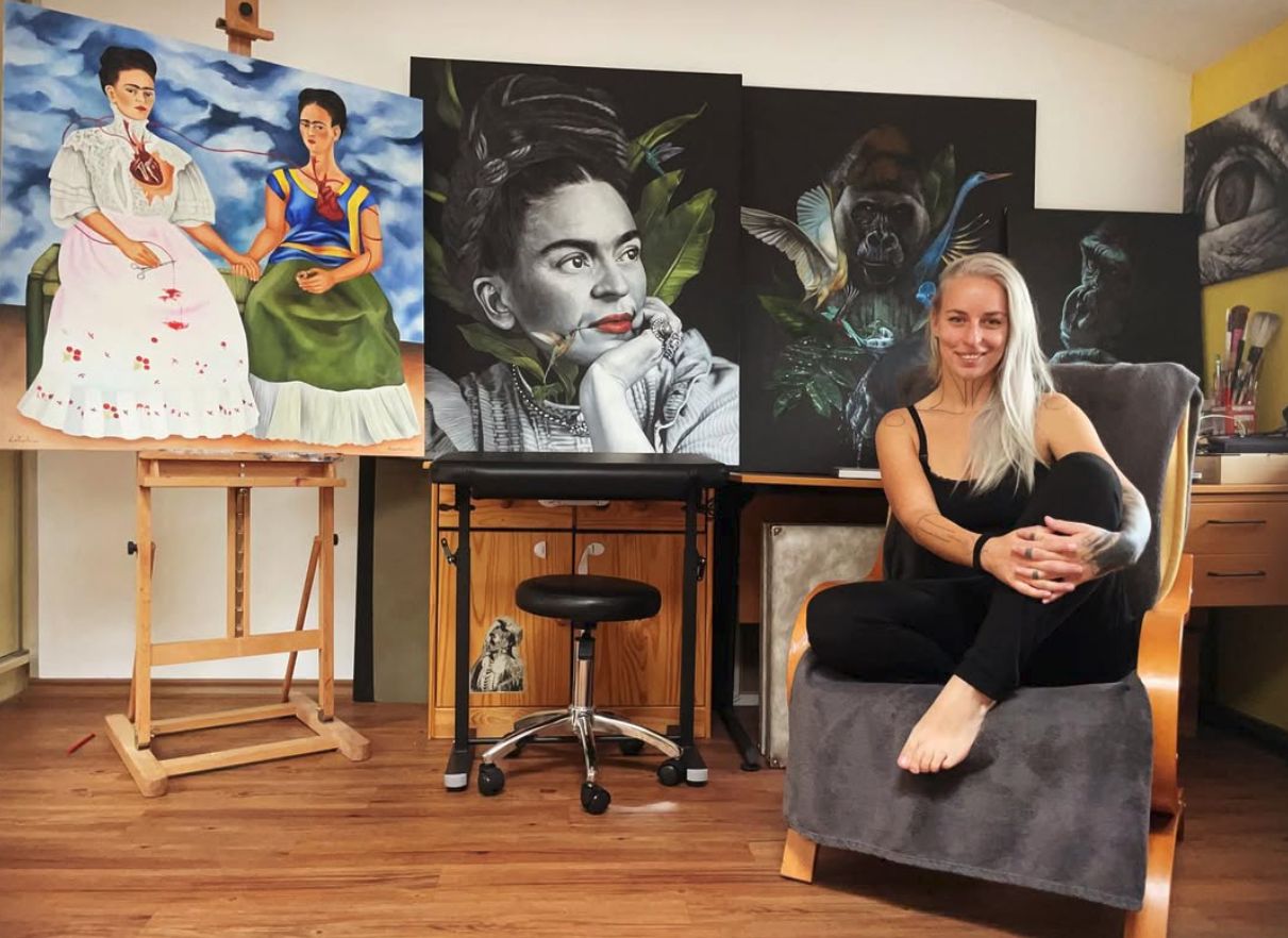 Michaela Krátká, aka LaPapula, sitting in an armchair among paintings